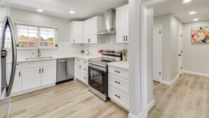 A modern kitchen with white cabinetry, stainless steel appliances, and a large window. - Near Fresno State & Malls! Family-friendly Home (Fresno)