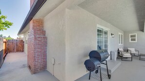 A covered patio with a brick chimney, a grill, and a seating area with a table and chairs. - Near Fresno State & Malls! Family-friendly Home (Fresno)