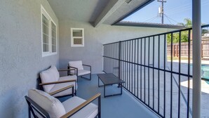 A covered balcony with a pool, a small table, and two chairs. - Near Fresno State & Malls! Family-friendly Home (Fresno)