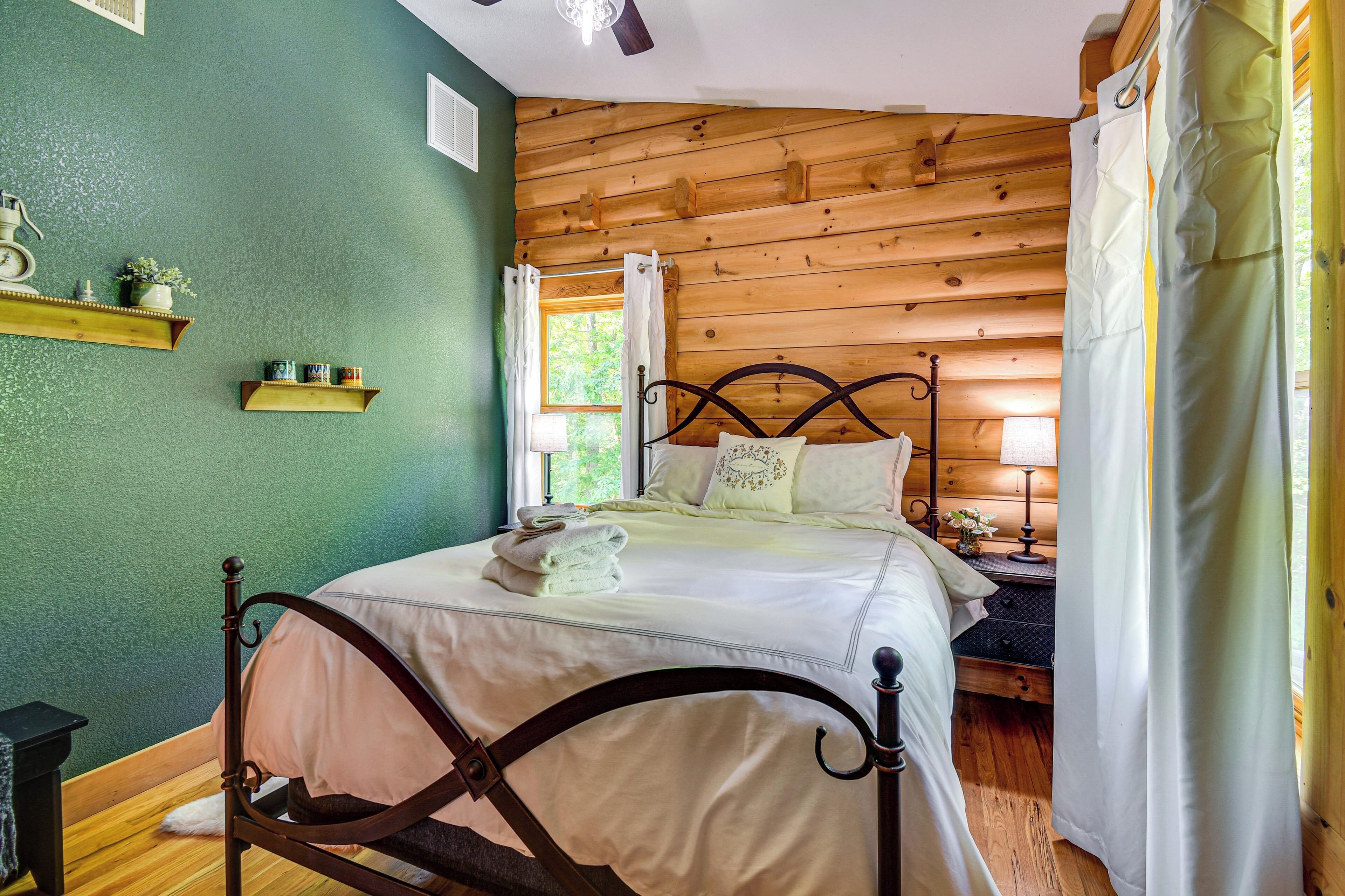 A wooden cabin bedroom with a bed, a nightstand, a lamp, and a window with curtains.