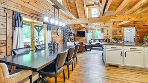A wooden cabin interior with a dining area, kitchen, and living space. - Hot Tub & Patio: Bedford Log Cabin on 10 Acres! (Moneta)