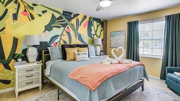 A bedroom with a bed, nightstands, a ceiling fan, a window with curtains, and a colorful wall mural.