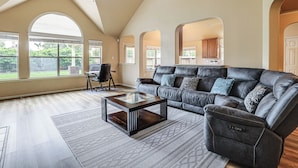 A spacious living room with a dark leather sofa, a glass-top coffee table, and a ceiling fan. - Feel at Home: Quiet Neighborhood, Emtek Smart Lock (Spring)