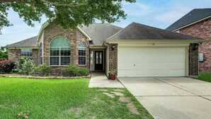 A two-story brick house with a garage, a front yard, and a large window. - Feel at Home: Quiet Neighborhood, Emtek Smart Lock (Spring)