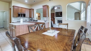 A spacious kitchen with wooden cabinets, a central island, and a dining area with a wooden table and chairs. - Feel at Home: Quiet Neighborhood, Emtek Smart Lock (Spring)