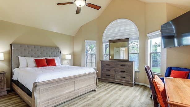 A bedroom with a large bed, a dresser, a chair, and a TV. - Feel at Home: Quiet Neighborhood, Emtek Smart Lock (Spring)