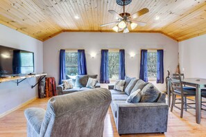 A living room with a ceiling fan, a TV, a sofa set, and a dining table. - Lake, Golf & More! Getaway in Center Barnstead (Center Barnstead)