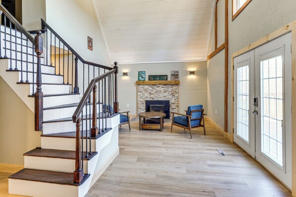 A staircase with wooden railings, a fireplace with a stone surround, and a seating area with a table and chairs. - Lake, Golf & More! Getaway in Center Barnstead (Center Barnstead)