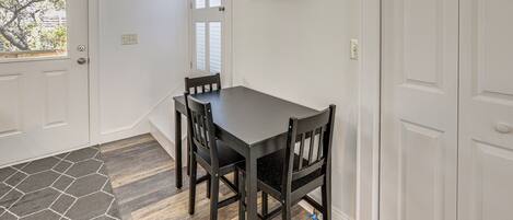 A dining area with a table and chairs, a door, and a wall-mounted picture.