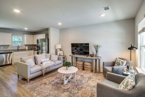 A modern living room with a sofa, armchair, coffee table, and a TV.