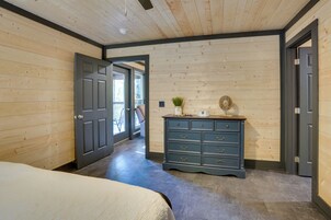 Un dormitorio con una cama, un aparador y una puerta que da a otra habitación.
