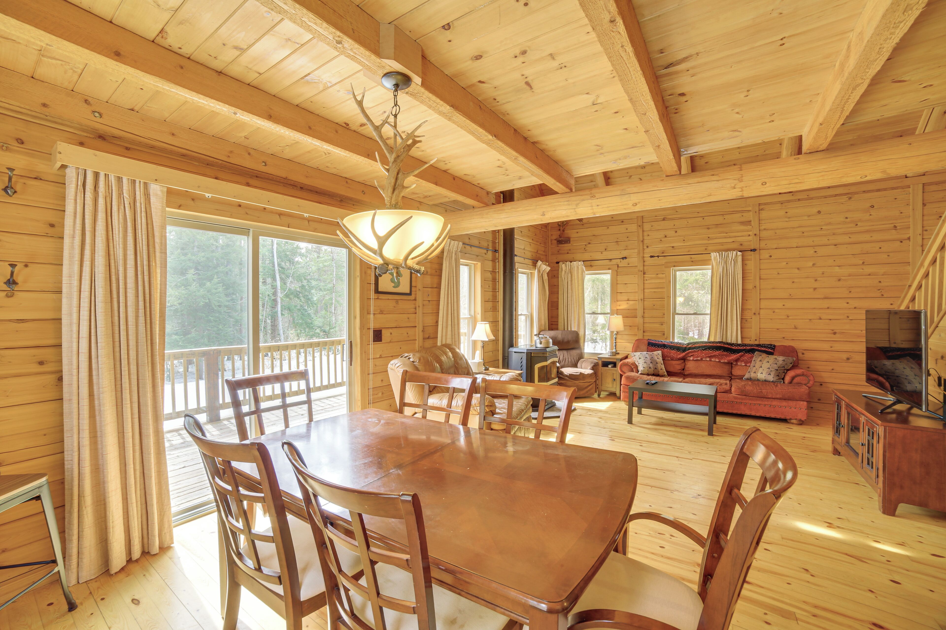 A wooden cabin with a dining table, chairs, a sofa, and a television.