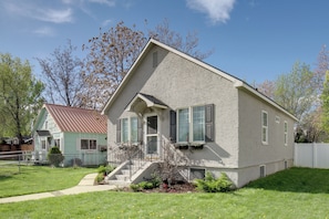 A two-story house with a front porch, a small staircase, and a fenced yard.