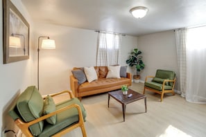 Ein Wohnzimmer mit Sofa, Sessel, Couchtisch und Stehlampe.