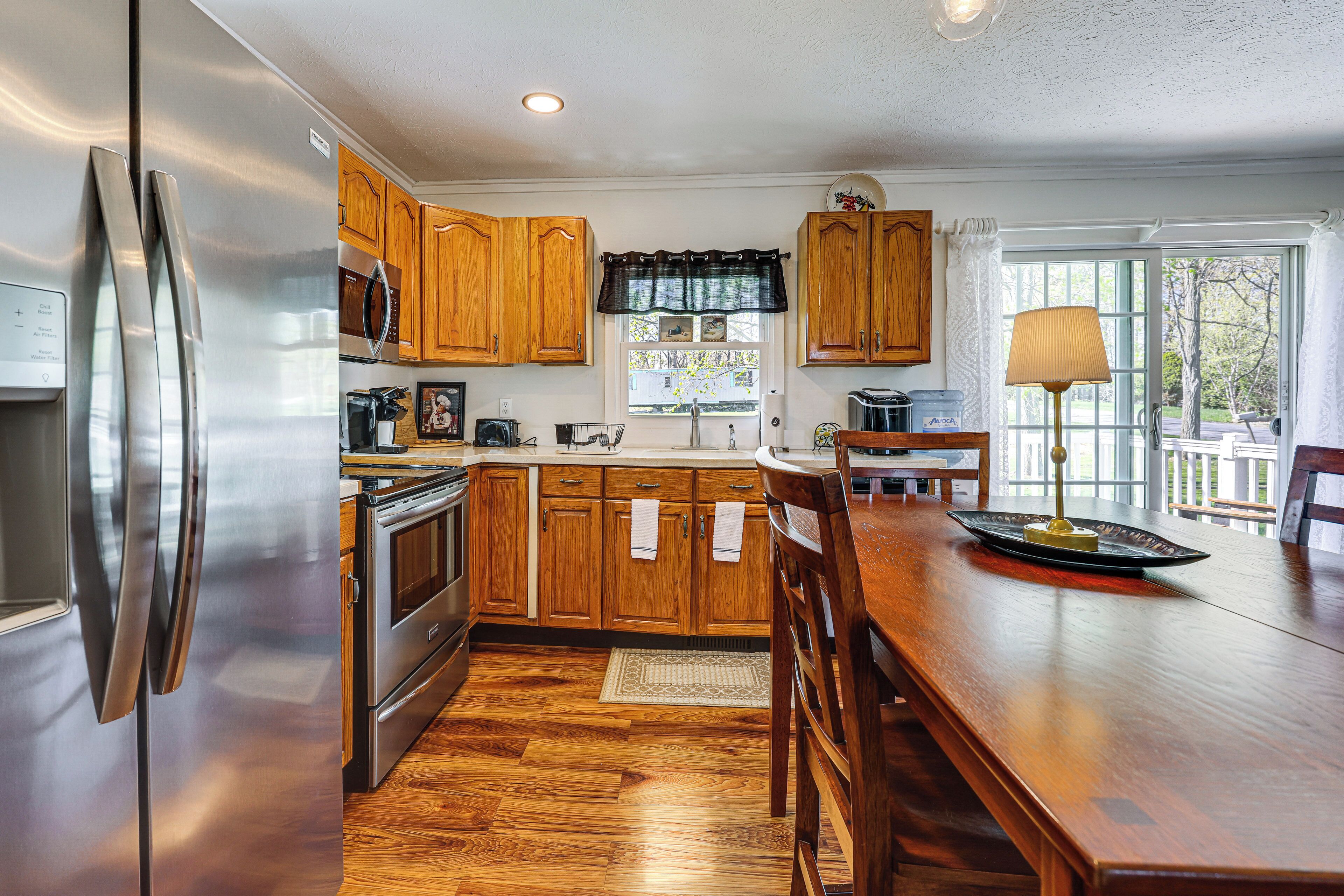 A kitchen with wooden cabinets, stainless steel appliances, and a dining area with a table and chairs.