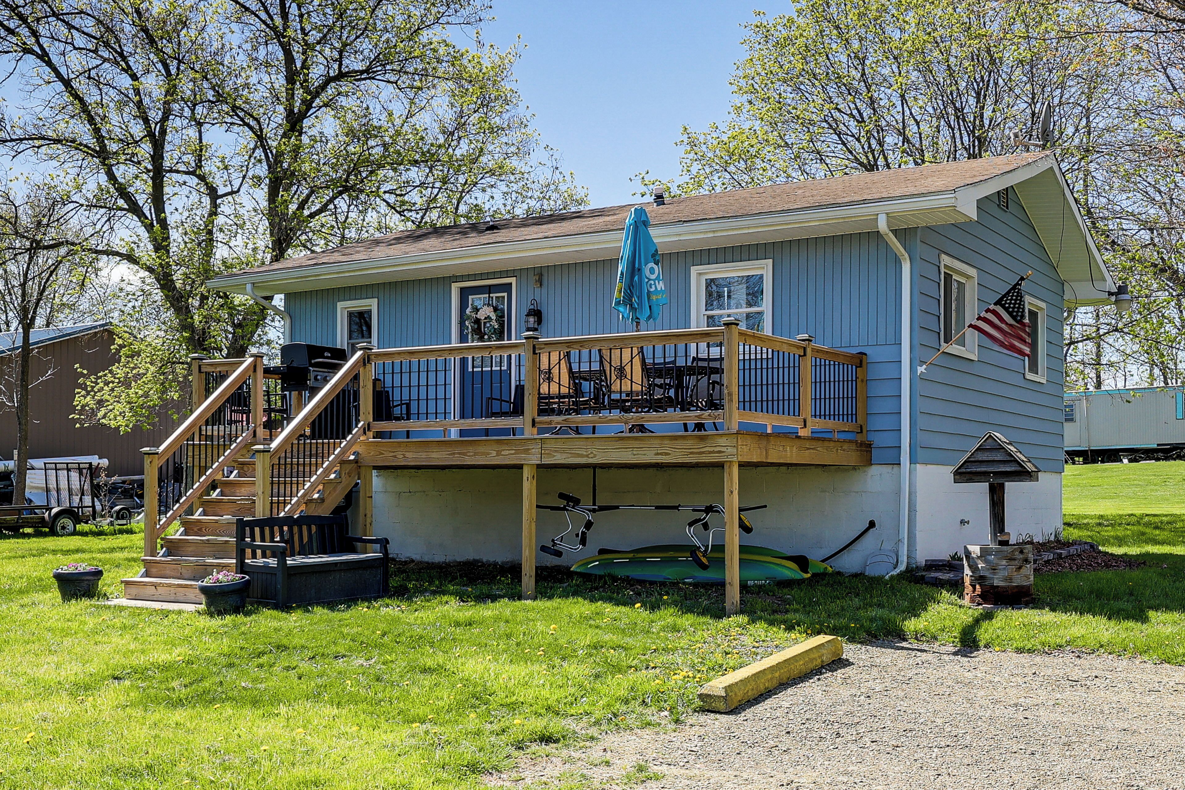 A two-story house with a deck, a flag, and a mailbox.