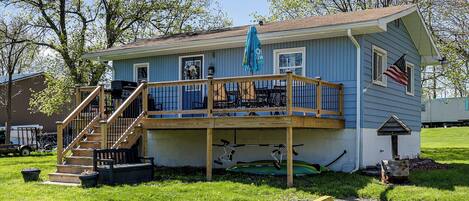 A two-story house with a deck, a flag, and a mailbox.