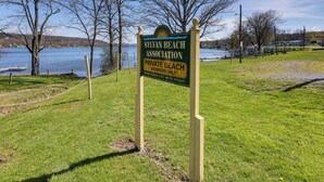 A sign for Silvan Beach Association Private Beach, with a grassy area and trees in the background. - Dog-friendly Waneta Lake Home w/ Lake Access! (Hammondsport)