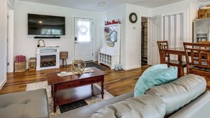 A living room with a fireplace, a television, and a dining area with wooden furniture. - Dog-friendly Waneta Lake Home w/ Lake Access! (Hammondsport)