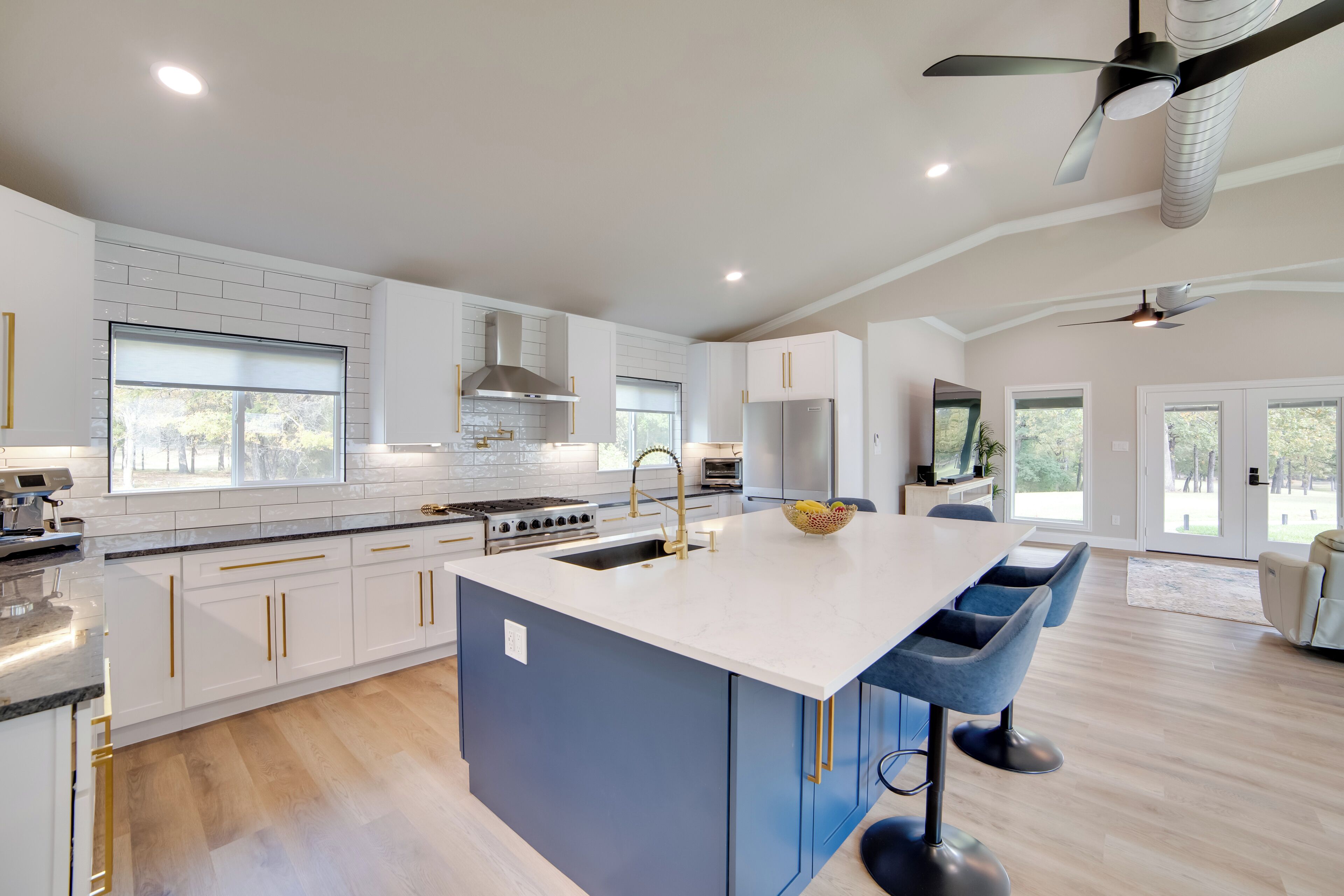 A modern kitchen with white cabinets, a central island, and a dining area with bar stools.