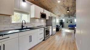 Una cocina moderna con armarios blancos, un refrigerador de acero inoxidable y techo de madera.