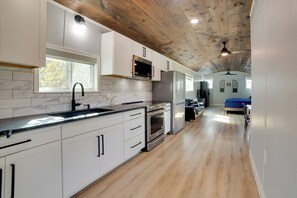 Una cocina moderna con armarios blancos, un refrigerador de acero inoxidable y techo de madera.