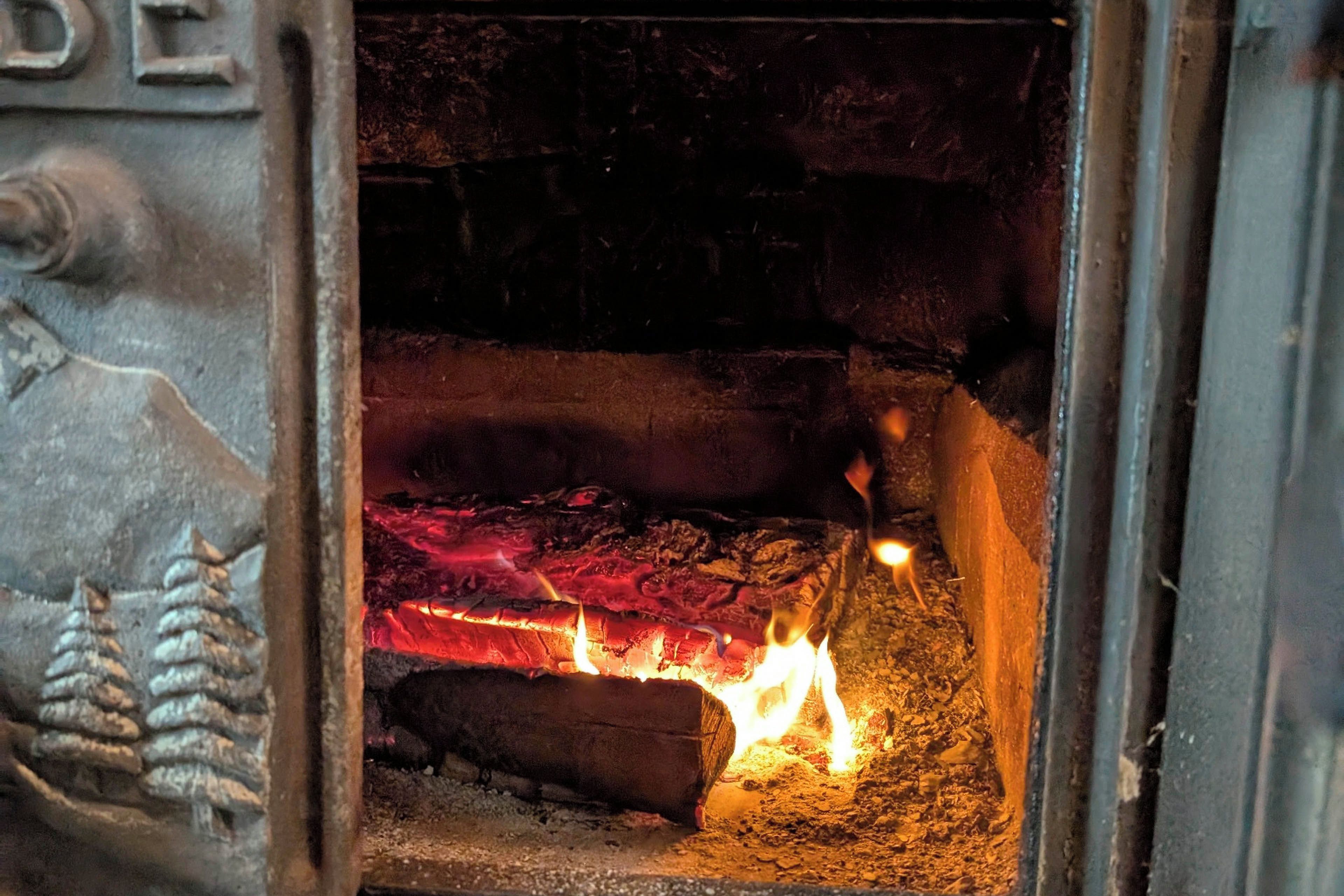A close-up of a fireplace with burning logs, visible through a metal grate.