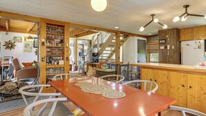 A wooden interior with a dining table, chairs, a staircase, and a kitchen area. - Catskills Serenity! Cozy Vintage Cabin on 10 Acres (Grahamsville)