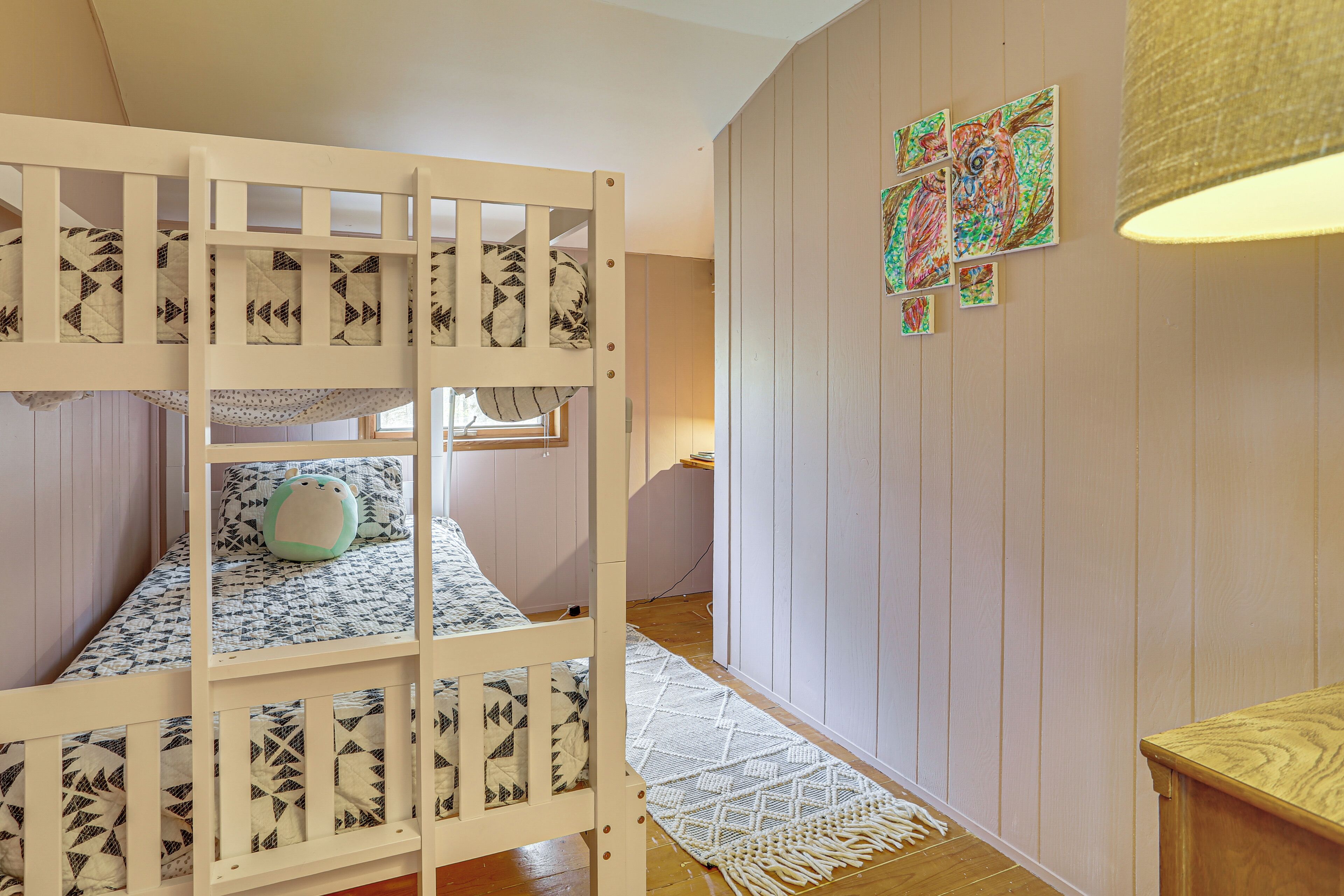 A bunk bed with patterned bedding, a woven rug, and wall art.