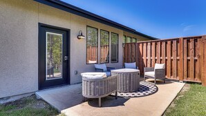 Un patio con mobiliario de mimbre y valla de madera.
