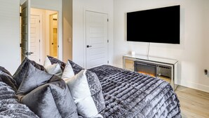 Un dormitorio con cama, televisor y chimenea.
