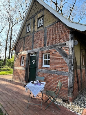 En traditionel murstensbygning med en grøn dør, et lille bord med dug og en stol foran.
