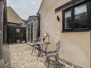 A patio with a table and chairs, a lantern, and potted plants. - Rubys Den (Swindon)