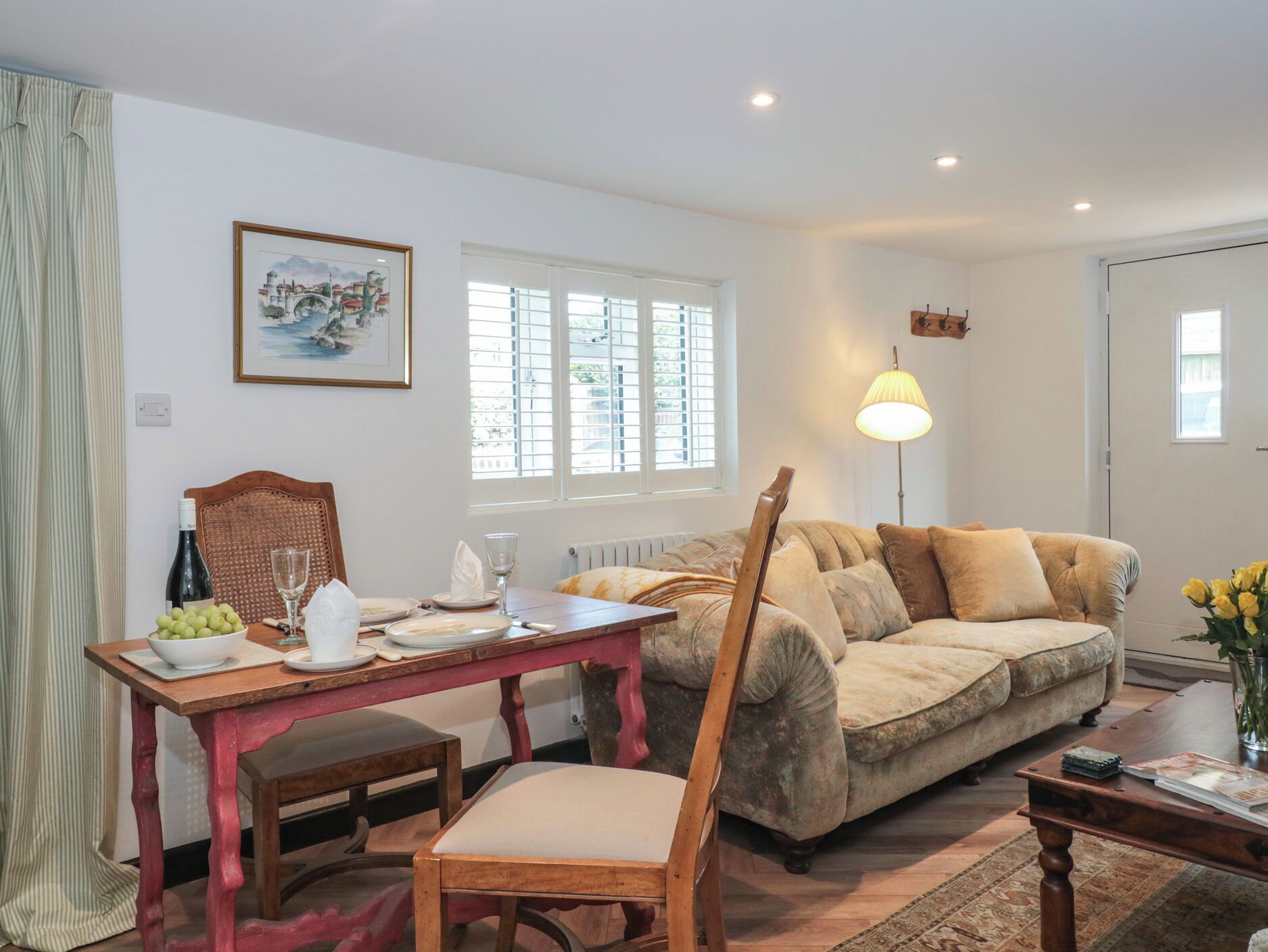 Un coin repas avec une table dressée pour deux personnes, un canapé et une lampe.