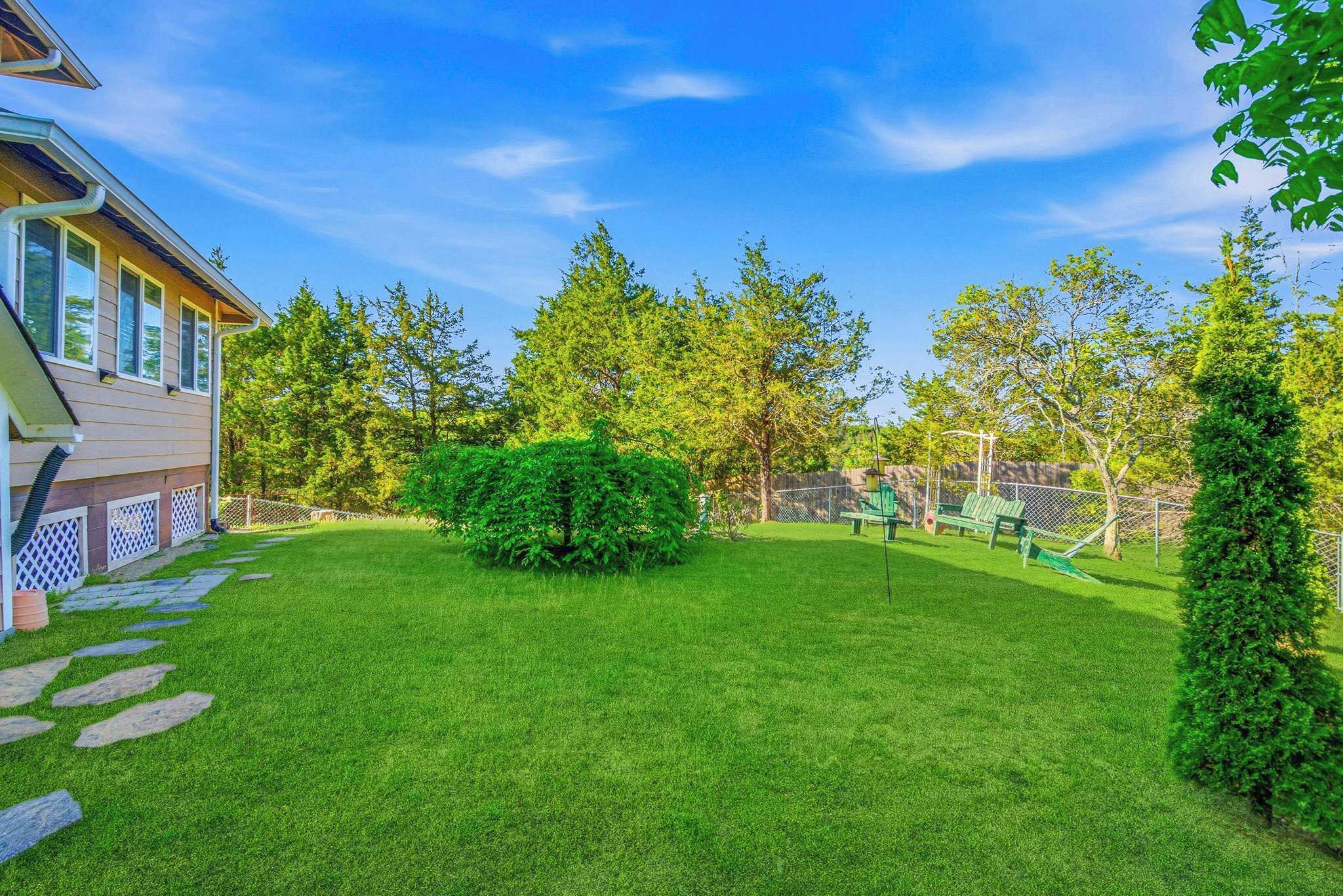 A well-maintained backyard with a lawn, a small bush, and a play area.