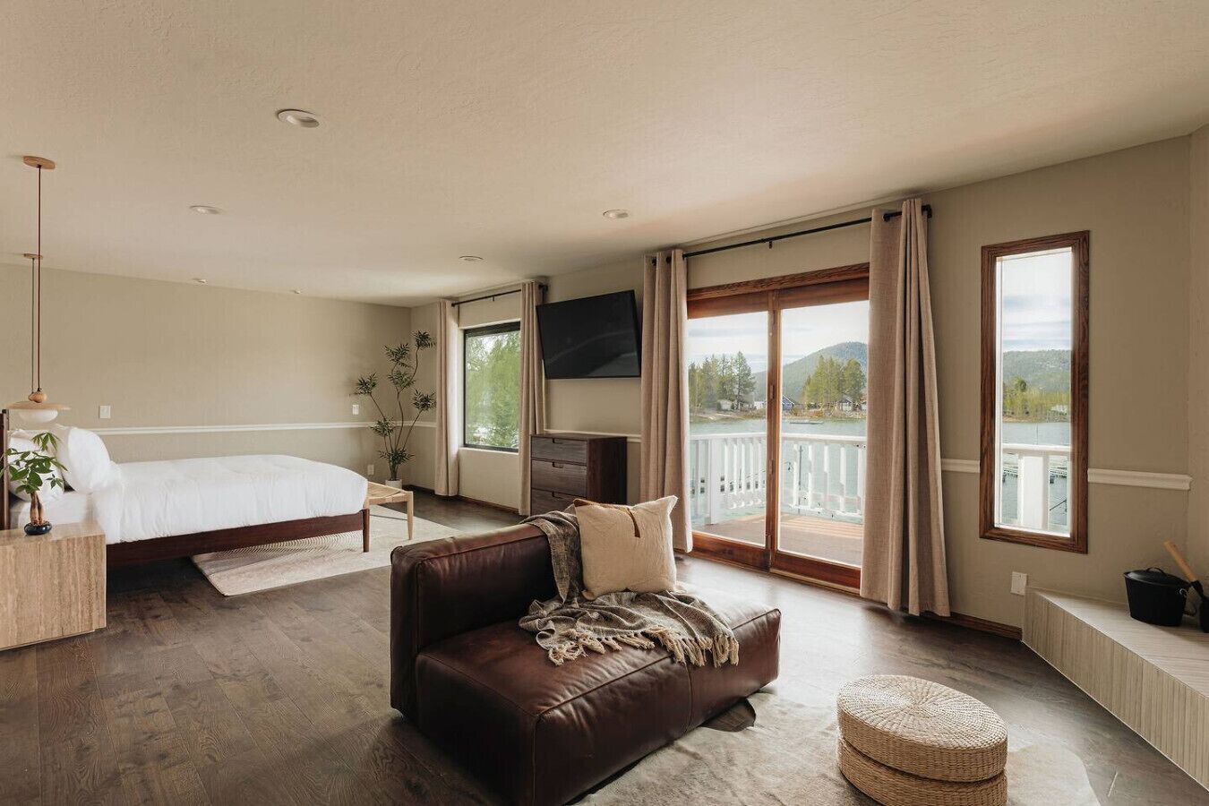 Un dormitorio con cama, sofá, televisor, ventana con vistas y balcón.