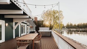 Um terraço com mesa e cadeiras, uma banheira de hidromassagem e vista para a água.