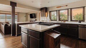 Cozinha moderna com uma ilha grande, armários escuros e vista para o exterior.