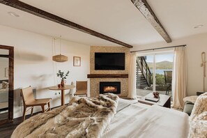 Ein Schlafzimmer mit Kamin, Fernseher, Essbereich und Seeblick.