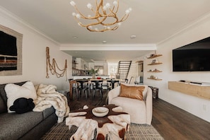A modern living room with a fireplace, a dining area, and a kitchen in the background.