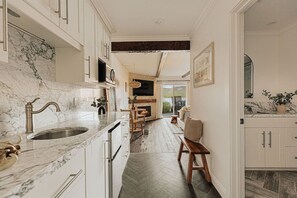 A kitchen with marble countertops, a sink, and cabinets. There is a dining area with a table and chairs, and a fireplace.