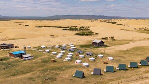 A desert landscape with yurts and a few buildings.
