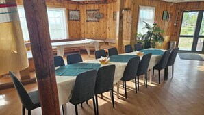 A dining area with a long table, chairs, and a potted plant.