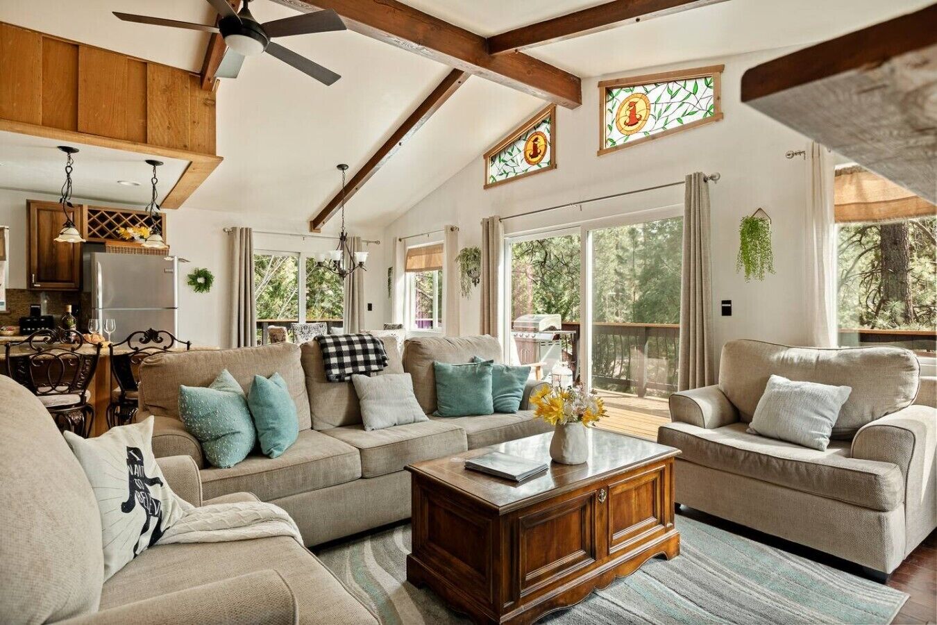 A spacious living room with a large sofa, a coffee table, and a dining area with a chandelier.