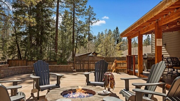 Eine Terrasss mit Adirondack-Stühlen, einem Steinkamin und einer Holzpergola.
