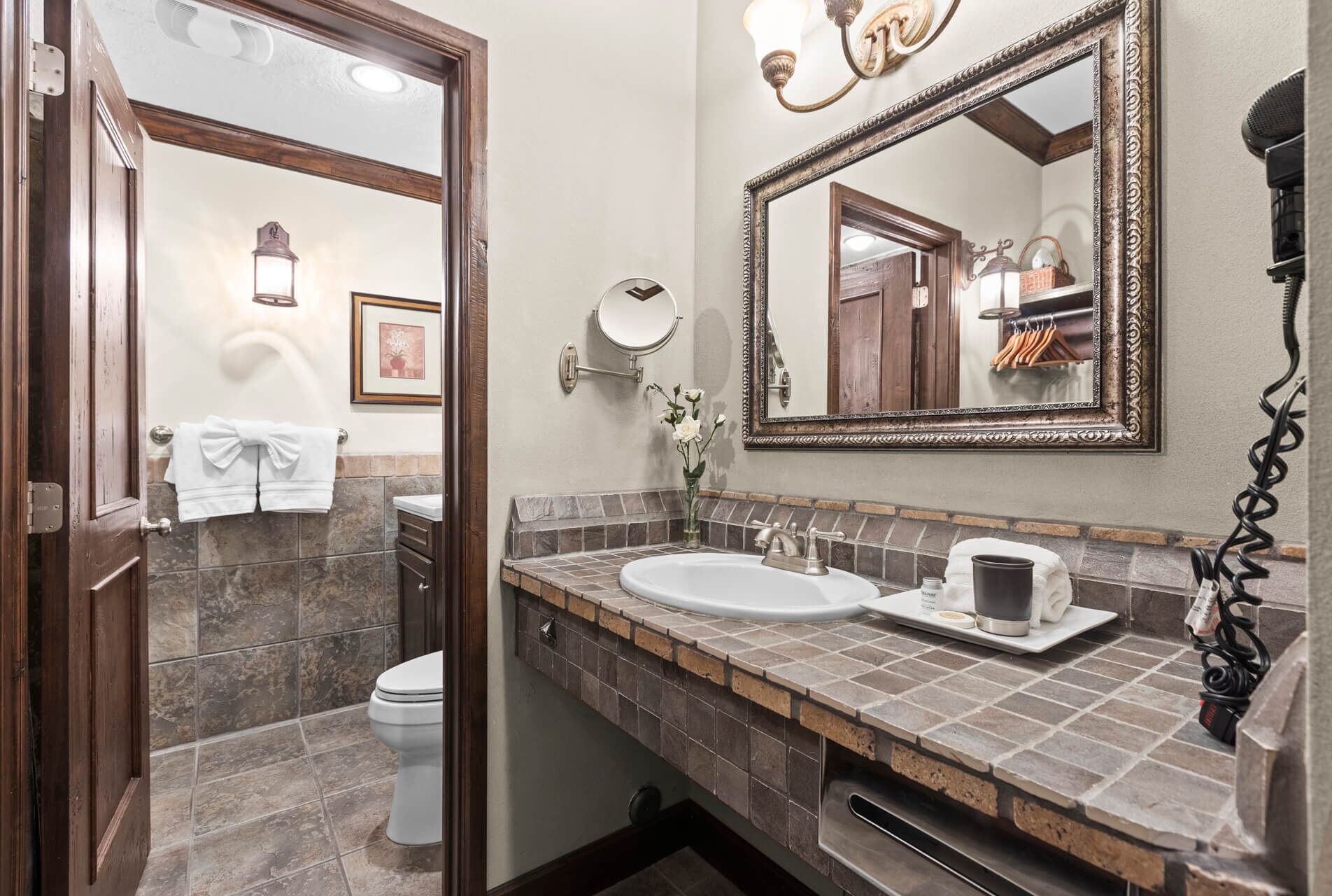 A bathroom with a marble sink, a mirror, a towel rack, and a toilet.
