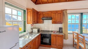 A kitchen with wooden cabinets, a stove, a microwave, and a refrigerator. - Guestready - Colon Eva (Fuencaliente de la Palma)