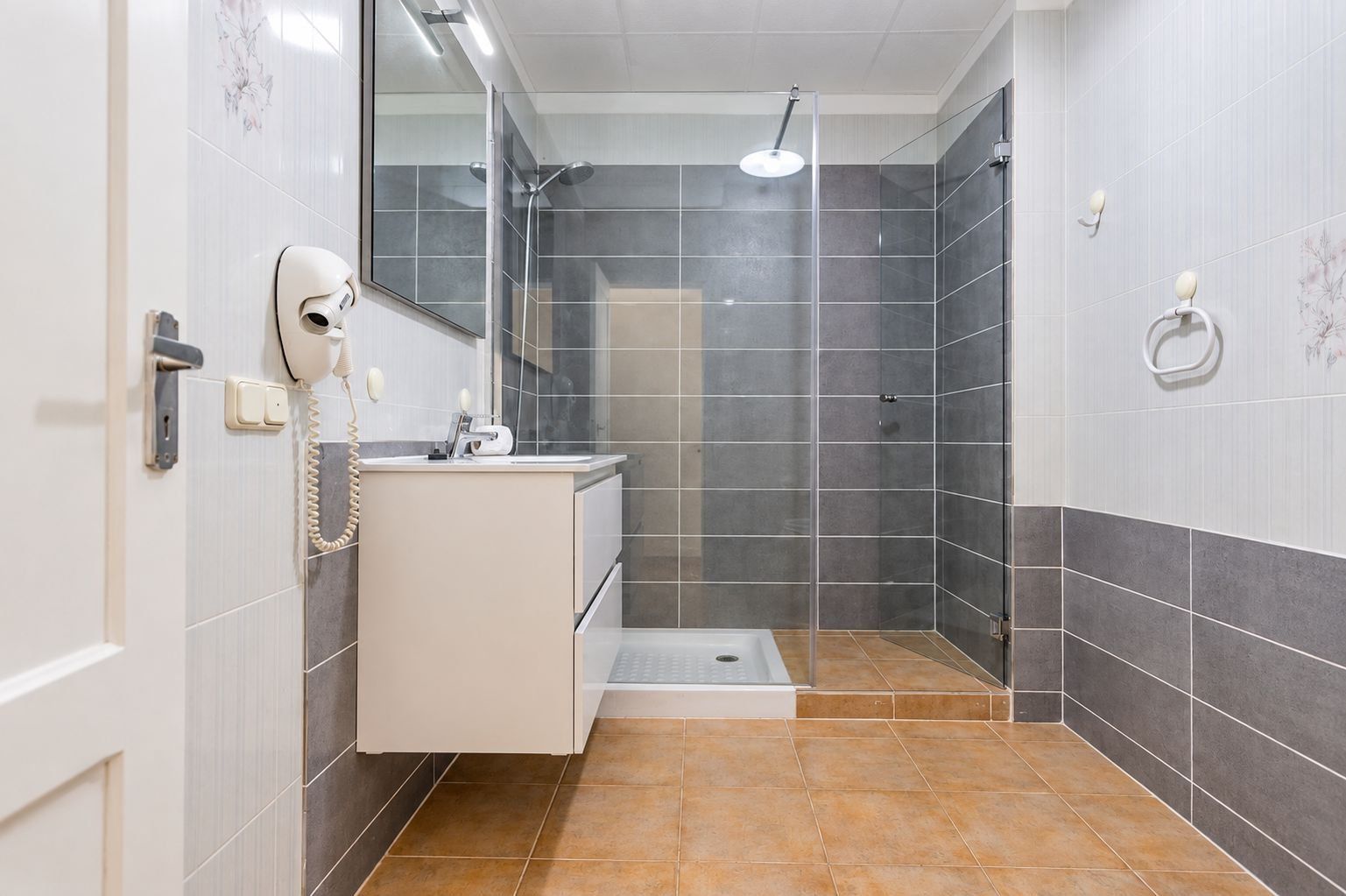 Ein Badezimmer mit Dusche, Toilette und Waschbecken mit Spiegel.