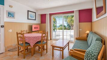 Una habitación con una mesa de comedor, sillas, un sofá, un televisor y vistas al exterior.