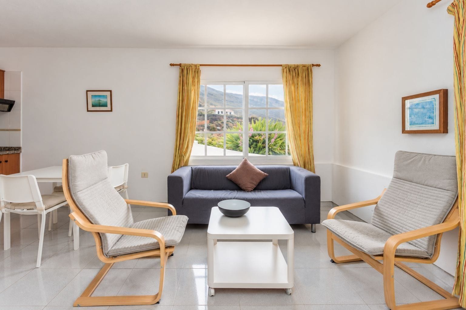 A modern living room with a sofa, two armchairs, a coffee table, and a dining area with a table and chairs.